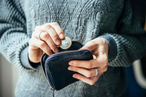 Mujer metiendo una moneda a la cartera