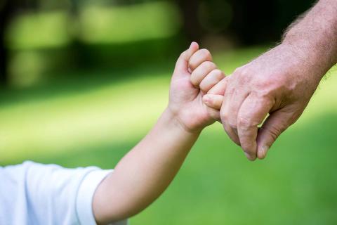 Mano adulta sujetando la mano de un niño