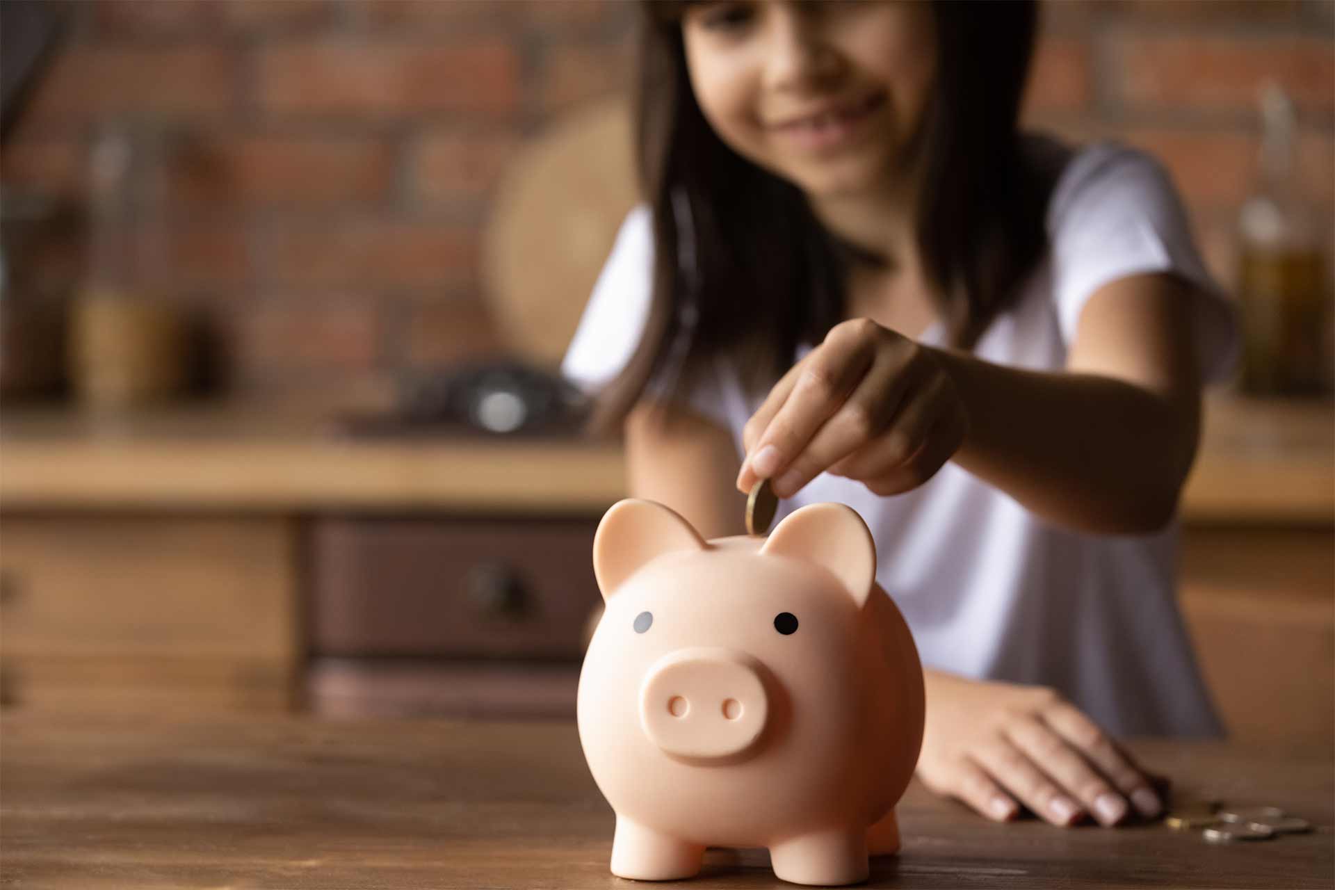 Niña metiendo una moneda en la hucha